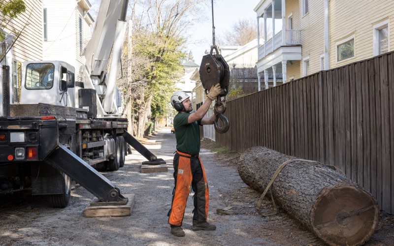 Worker setting the choker onto the crane hook block in a narrow Old Decatur alley before a pick.